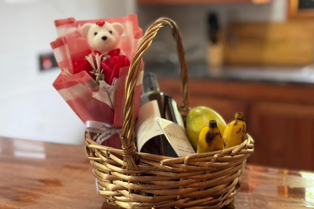A basket of fruit, flowers and a bottle waiting on the kitchen counter at AliBel Beach Villa