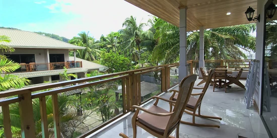 The covered balcony of the North family villa at Alibel Beach Villa, with rocking chairs looking over the garden