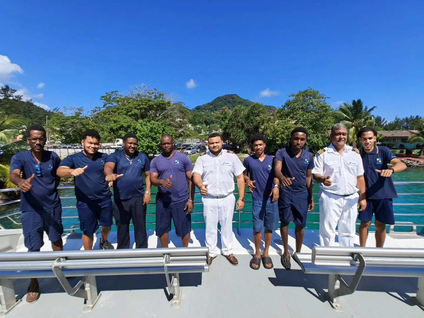 The crew of a Cat Cocos catamaran lined up along the rail of the top deck