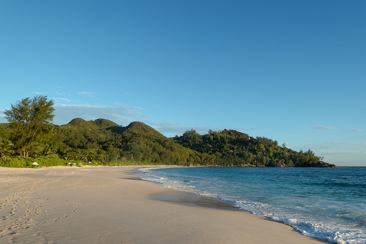 An empty beach at Anse Intendance on Mahé with a forested mountain ridge behind it.