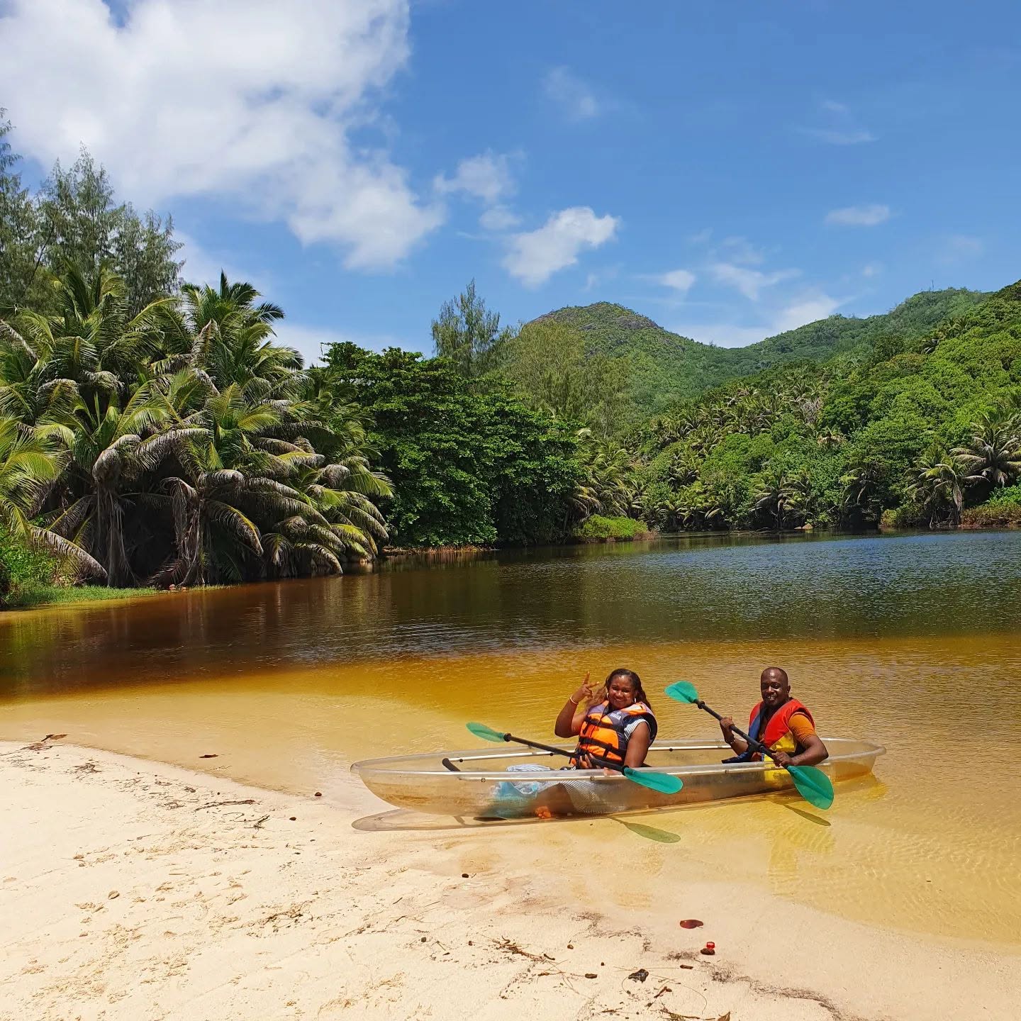 Kayakers on a golden-lit lagoon below green hills