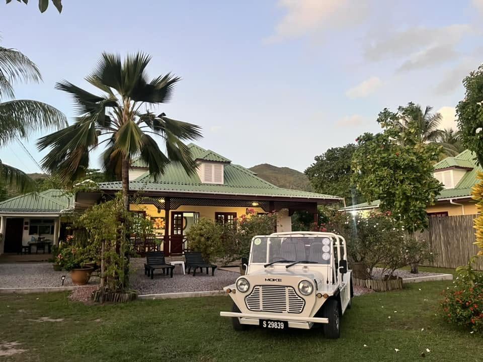 A cream modern Mini Moke on the lawn of a green-roofed Creole guesthouse in evening light