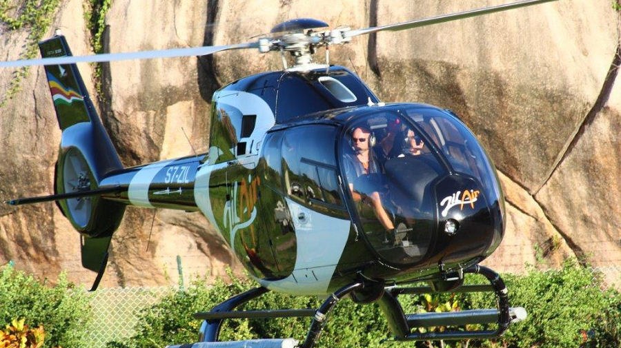 A Zil Air helicopter on the ground beside a granite boulder, passengers in the cabin