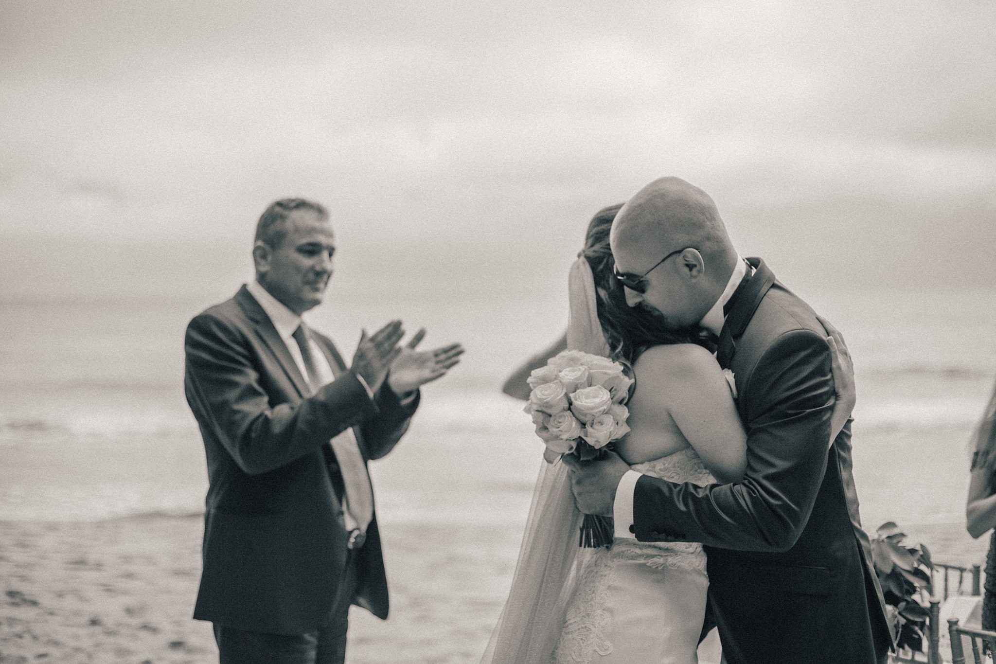 Black and white: a guest applauding as the couple embrace