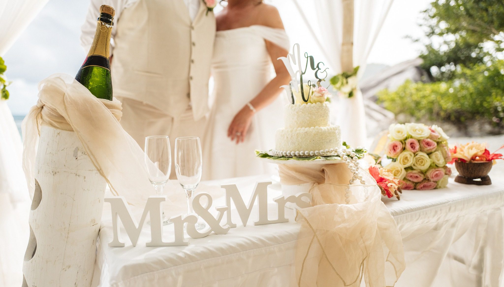 The cake table with champagne, roses and a Mr and Mrs sign