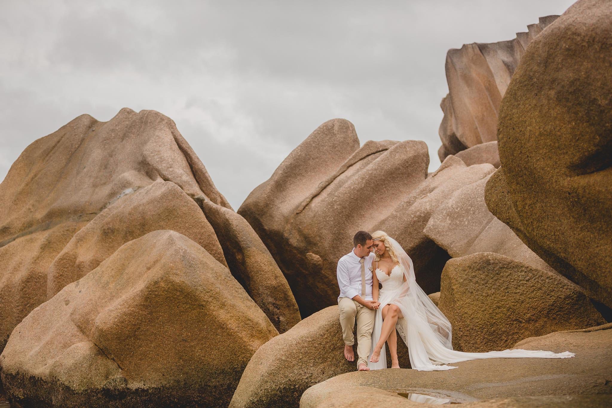 The couple sitting high in a granite formation above the beach