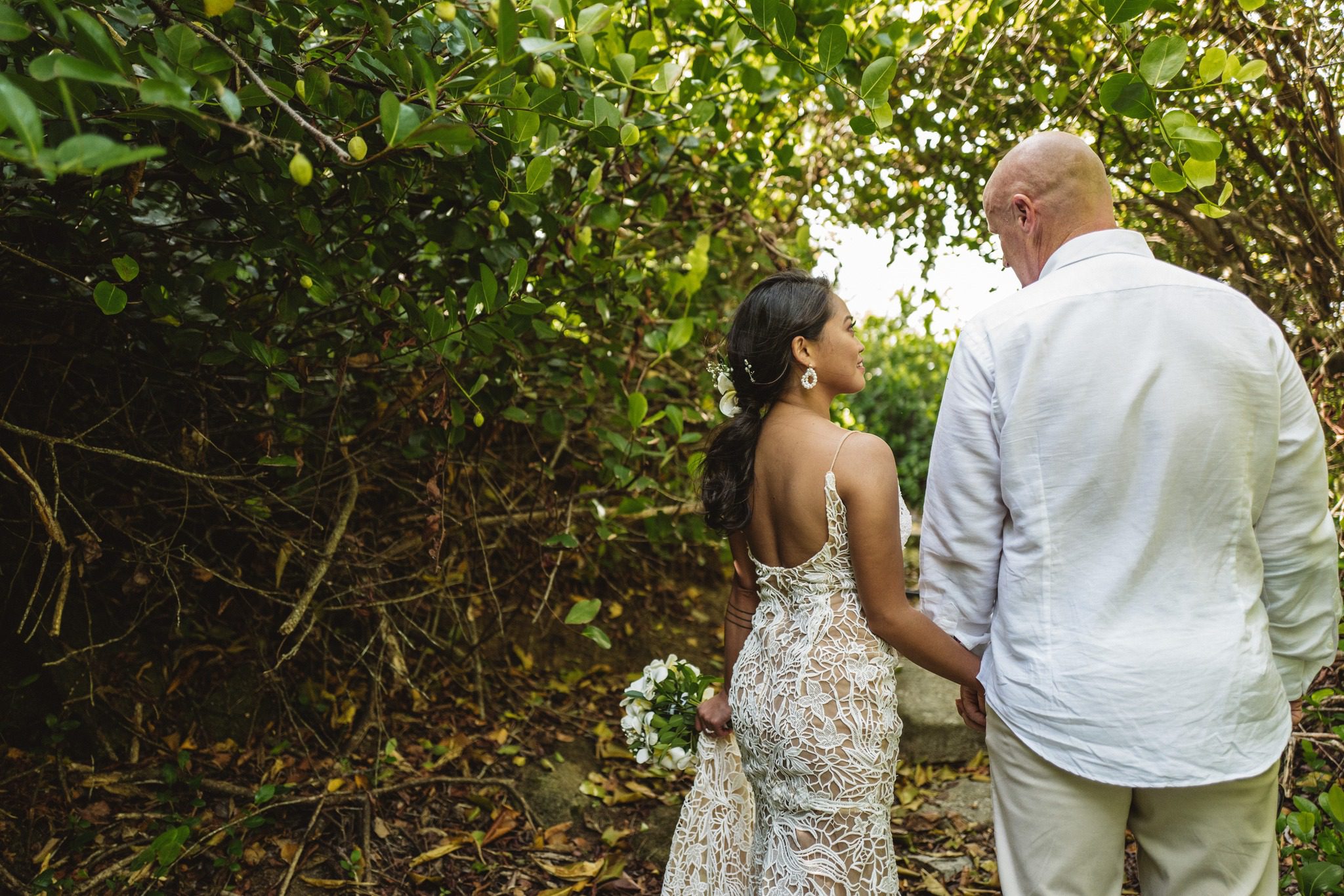 The couple hand in hand with their backs to us, looking out through the hedge to the water