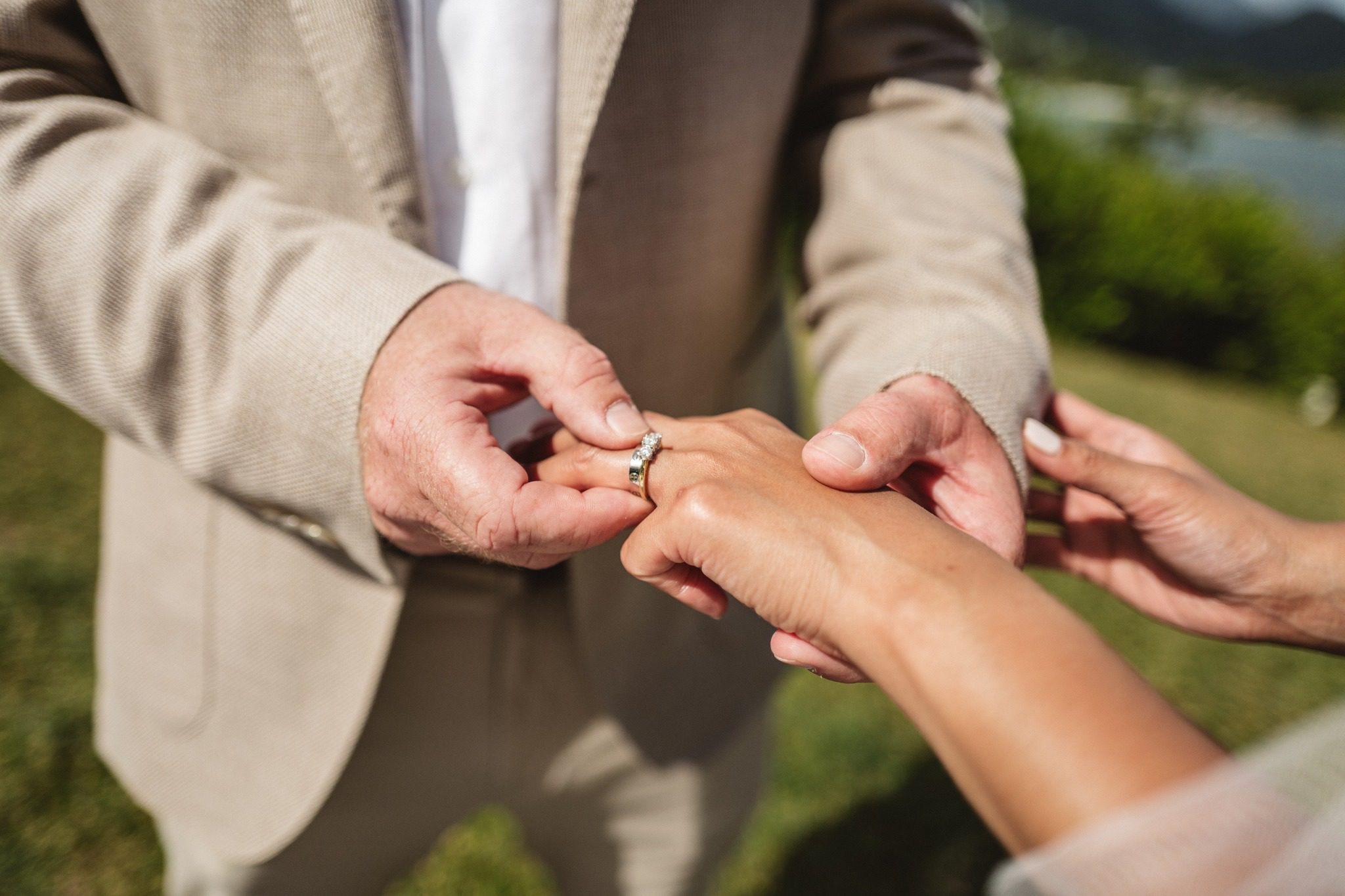 Close on the groom sliding the ring onto the bride's finger