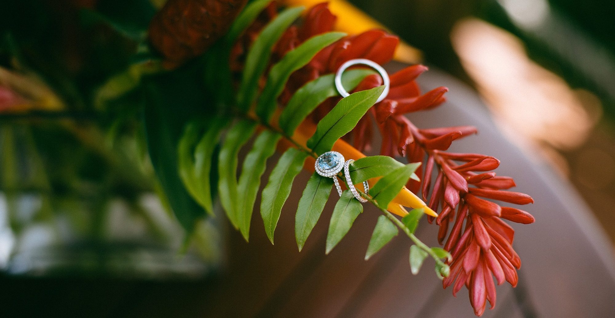 A wedding ring balanced on a red heliconia