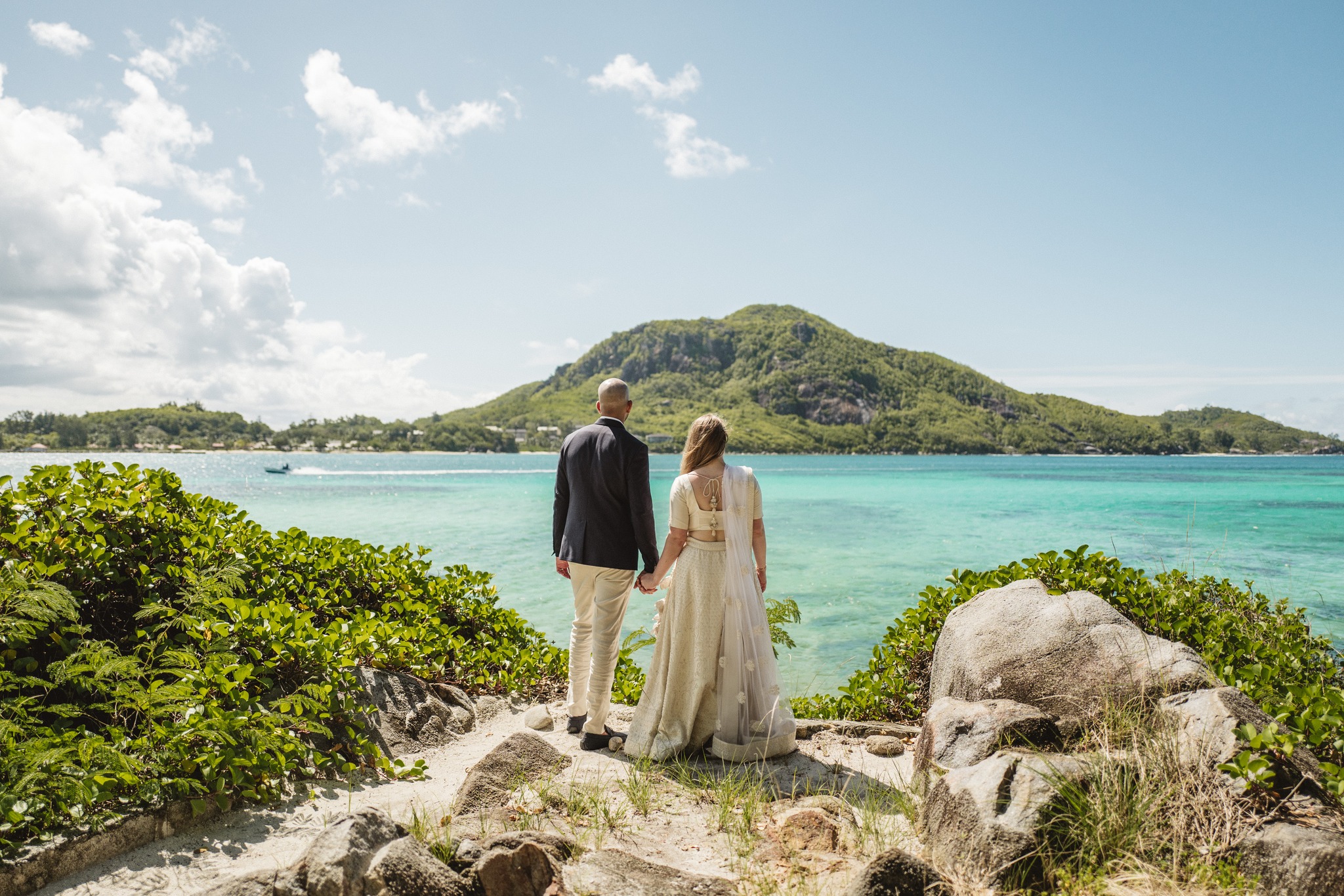 The couple on the rocks looking out at a green island across the water
