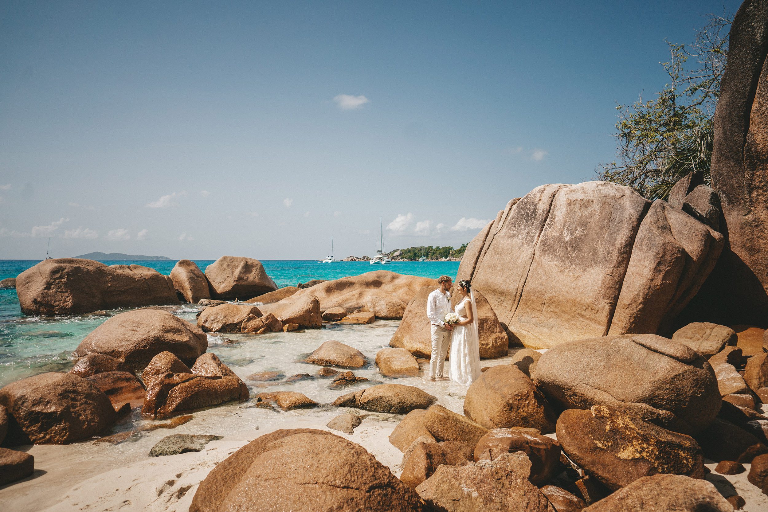 The couple among rust-coloured boulders on the shore
