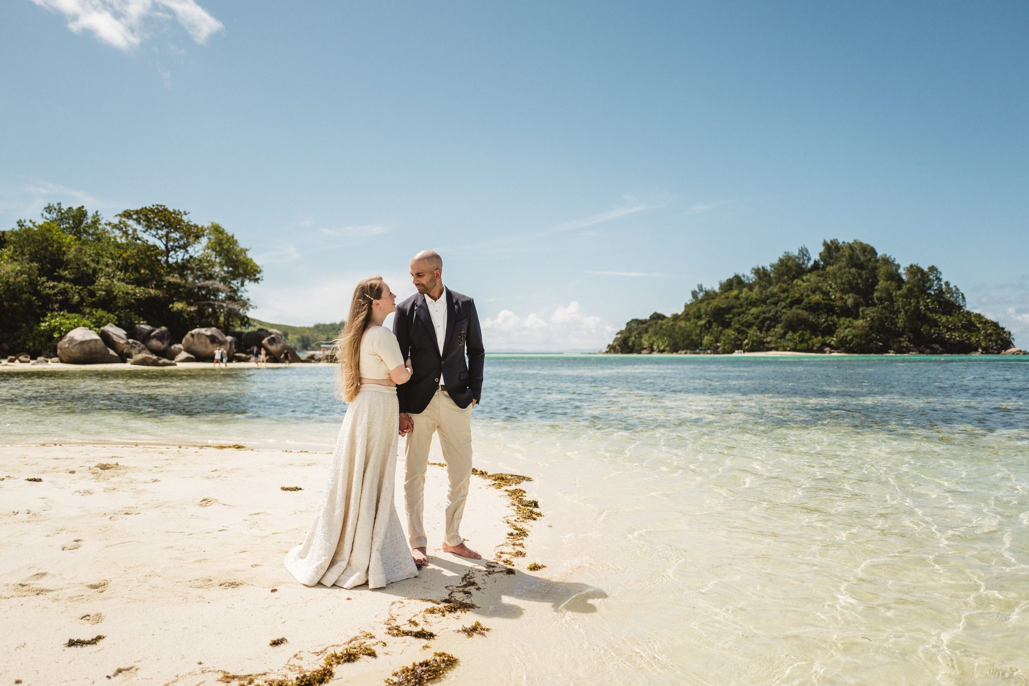The couple standing in shallow water on a sandbar, a wooded islet behind them