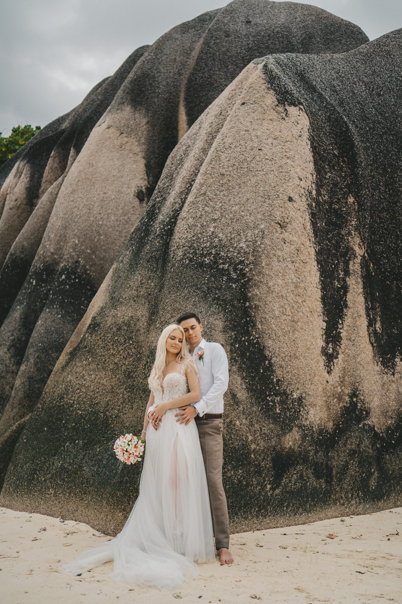 The couple against a wall of sculpted granite on the sand
