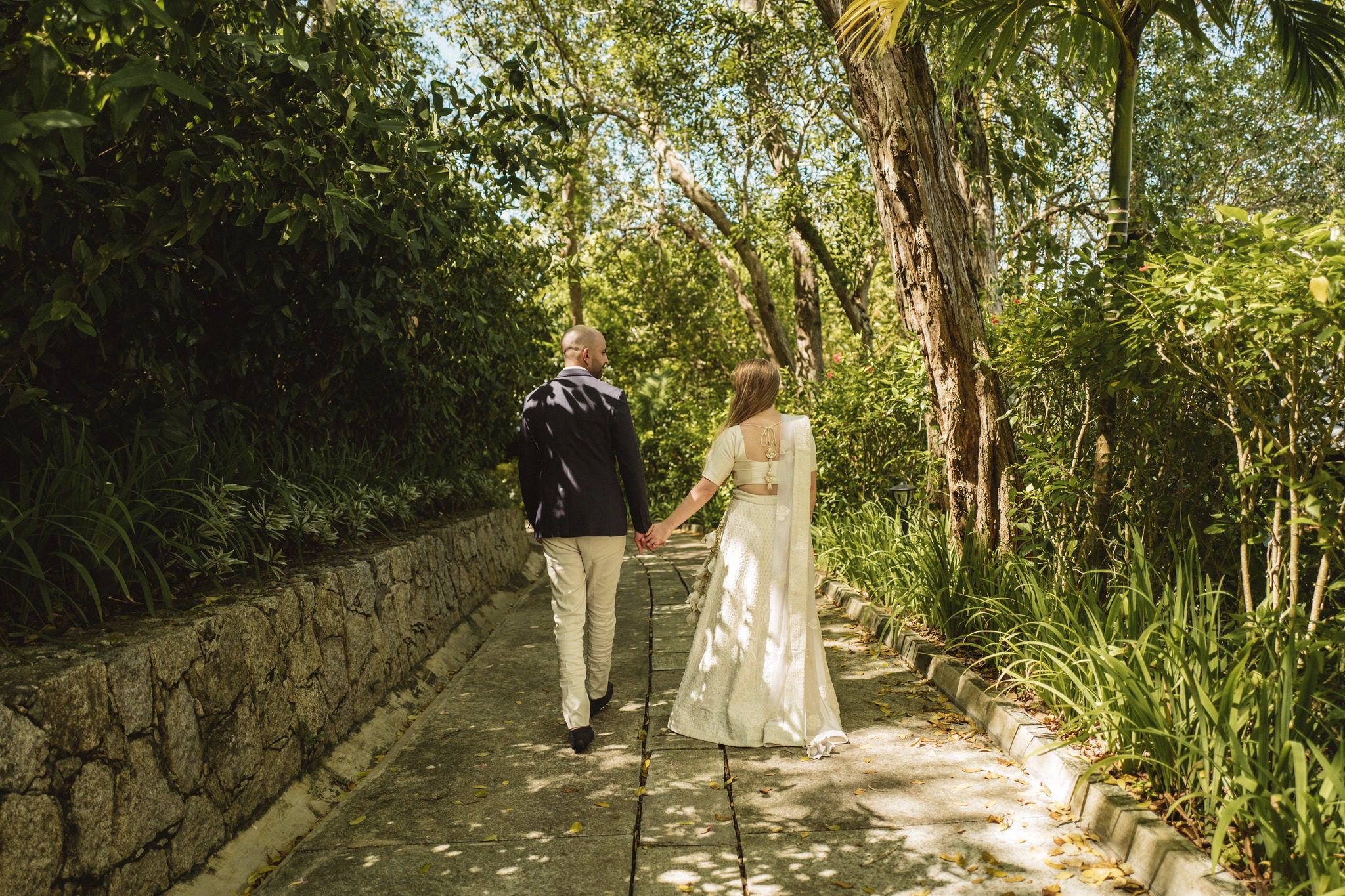 The couple walking a shaded stone path under trees