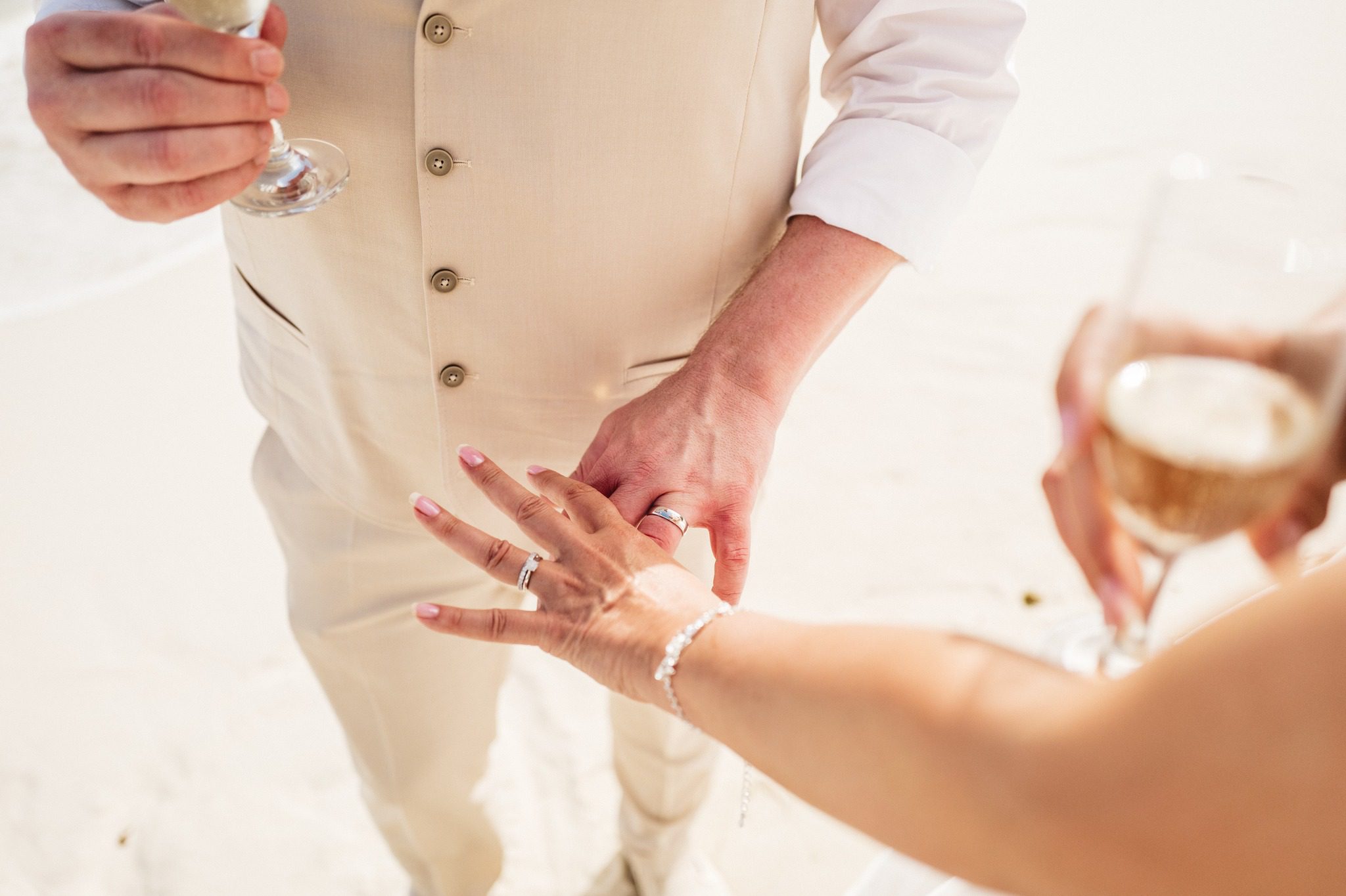 A toast on the beach, the bride's ring hand and the raised glasses