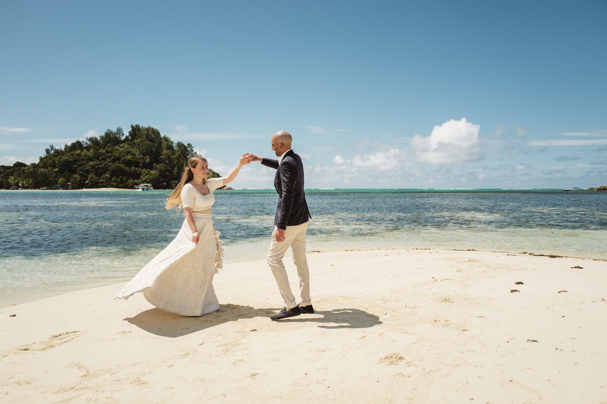 The groom turning the bride under his arm on an empty beach